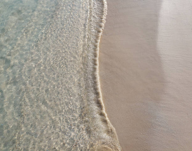 onda rasa de águas claras correndo sobre a praia de areia marrom limpa e fina. - sandy brown bay beach sand - fotografias e filmes do acervo
