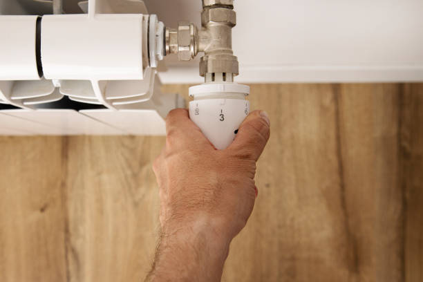 istock Man's hand changes the temperature on the heater with a regulator. Top view, flat lay 1428988188