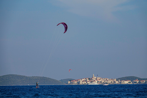 COPY SPACE: Athletic woman foilsurfs near the old town of Korcula on a sunny day