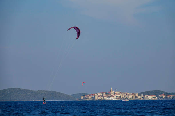 copy space: wysportowana kobieta floretsurfuje w pobliżu starego miasta korcula w słoneczny dzień - kiteboarding sunlight croatia dalmatia zdjęcia i obrazy z banku zdjęć