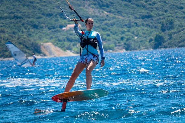 클로즈업: peljesac 반도를 따라 호일 보드에 여성 관광객 서핑을 장착하세요. - kiteboarding sunlight croatia dalmatia 뉴스 사진 이미지