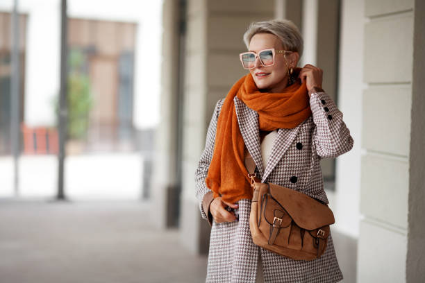 smiling woman outdoor portrait. short blonde hair fashion model wears stylish clothes, double-breasted jacket, leather handbag, ochre knitted scarf and glasses. fashion trend of autumn or spring - smiling clothing garment lifestyles imagens e fotografias de stock