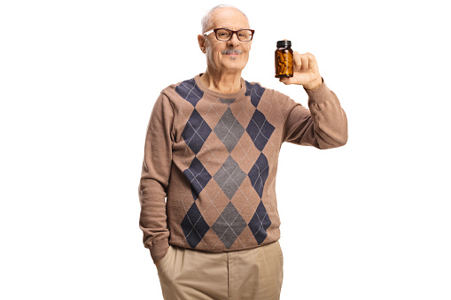 Mature man holding a bottle of pills isolated on white background