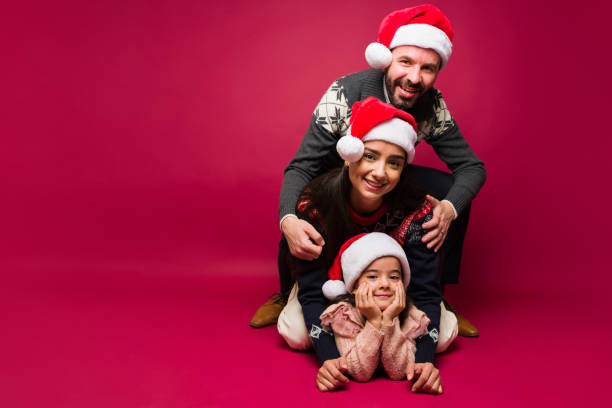 Excited smiling mom, dad and little kid having fun playing while celebrating christmas together