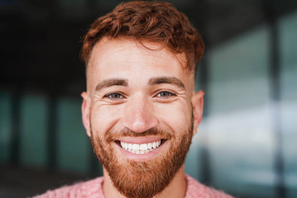 Young happy man smiling on camera outdoor - Focus on face stock photo