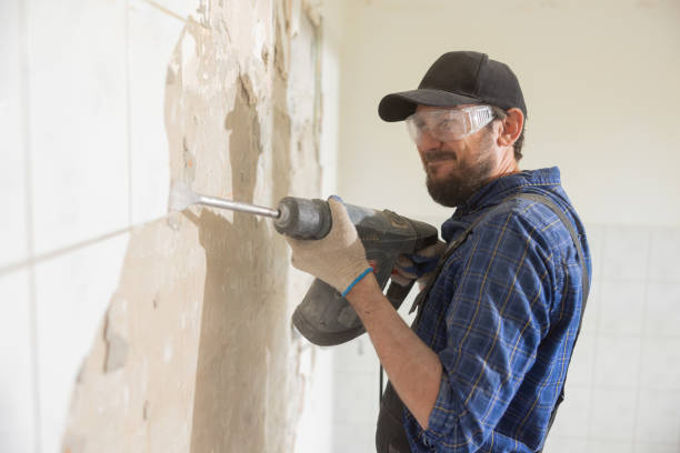 istock A focused man puts all strength while hammering tiles in kitchen bathroom. A man working on a house construction site during a renovation performs finishing work with protective goggles gloves 1428997944