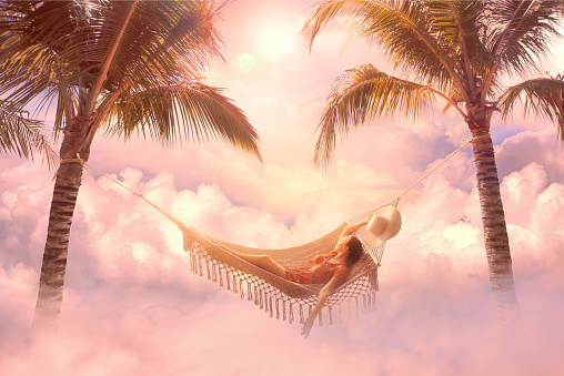 Dreamy summer screensaver with relaxed young woman relaxing in a hammock among clouds in pastel colors. Mixed media