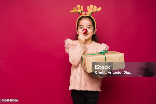 Adorable Girl Putting Up A Red Reindeer Nose For Christmas Stock Photo - Download Image Now