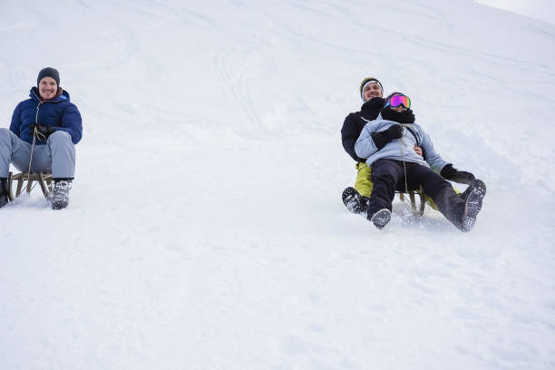 verrückte glückliche freunde, die spaß beim rodeln auf schneehohen bergen haben - switzerland hotel skiing people stock-fotos und bilder