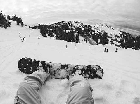 Pov of young man with snowboard looking the views on snow high mountains - Focus on his feet - Black and white editing