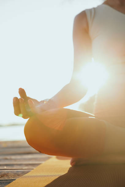 Primo piano di una donna yogi seduta in una posa di loto e meditando. - foto stock