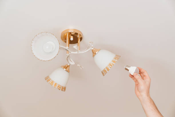 istock A male electrician changes the light bulbs in the ceiling light. 1429006076