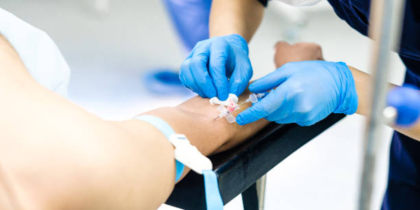 The doctor inserts a dropper needle into the patient's arm. A doctor in sterile gloves inserts a dropper needle into the patient's hand. saline drip stock pictures, royalty-free photos & images