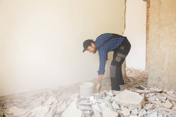 istock A man in a work suit with a baseball cap cleans up in an apartment under renovation, picks up debris from the floor left after demolishing walls with a shovel 1429006159