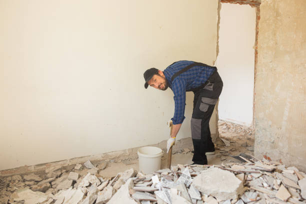 istock A man in a work suit with a baseball cap cleans up in an apartment under renovation, picks up debris from the floor left after demolishing walls with a shovel 1429007584