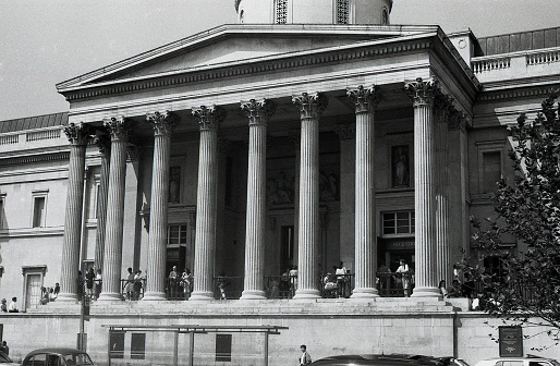 London, England - August 5, 1989: People stand in front of the National Gallery in Trafalgar Square. Designed by William Wilkins, the art museum was completed in 1838.