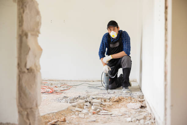 istock Removing a concrete floor with a hand hammer. Concrete rubble on the construction site of a house. Destruction of old tiles. Male construction worker fiercely working in overalls and protective mask 1429007720