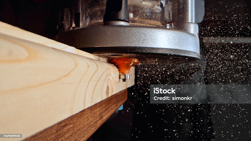 Router on wooden plank Close-up of router moving on wooden plank in workshop. Carpentry Stock Photo