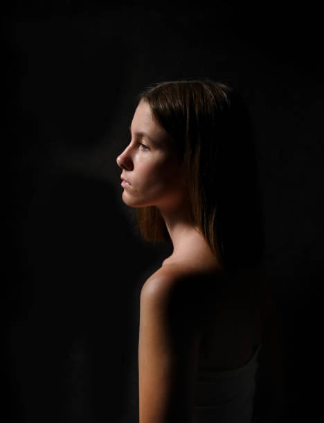 Low key portrait of a young girl in profile stock photo