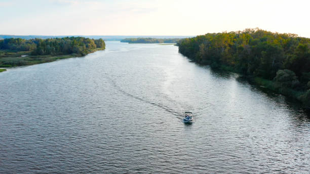 Photo from drone above a river with a slow drifting speedboat while sunset with people on board. Aerial view of driving powerboat on lake in the summer.