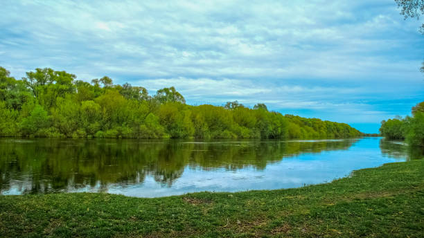 istock Beautiful spring green landscape with  flowing river and  fluffy clouds. Beautiful nature on spring. No people. Photo of a  summer landscape with a cloudy skies. 1429016515