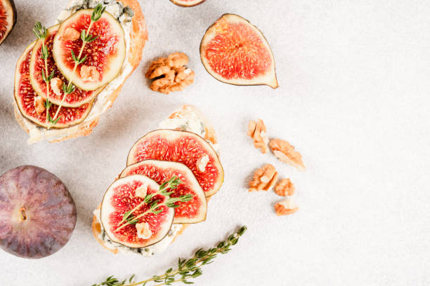 istock Healthy quick breakfast ideas - fresh bruschetta with ripe fig, cheese and herbs over white concrete table background. Top view, selective focus 1429019399