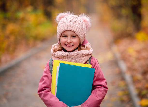 little girl with backpack holding folders - backpack student report card education imagens e fotografias de stock