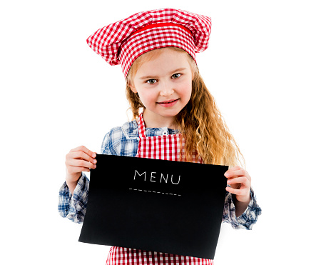 Little girl in chef uniform holding blank menu paper, isolated on a white background