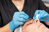 Professional beautician cleaning woman's skin from acne and blackheads.