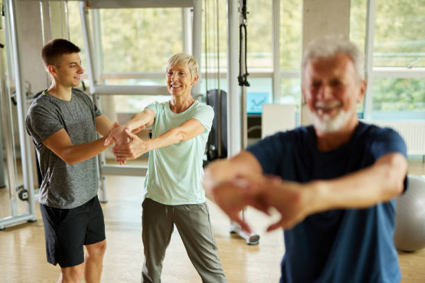 istock Senior couple doing stretching exercises with personal trainer at the gym 1429025655
