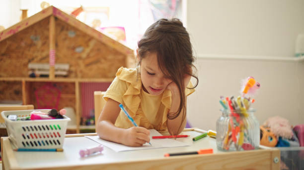 istock Little girl drawing while sitting at the table in her room 1429027036
