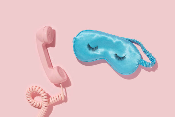 Creative layout with pink retro phone handset and sleep mask with false eyelashes on pastel pink background. 80s or 90s retro fashion aesthetic telephone concept. Minimal romantic handset cosmetic beauty Valentines day idea. diseño creativo con auricular de teléfono retro rosa y máscara para dormir con pestañas postizas sobre fondo rosa pastel. concepto de teléfono estético de moda retro de los años 80 o 90. minimalista romántico teléfono cosmético belleza idea del d