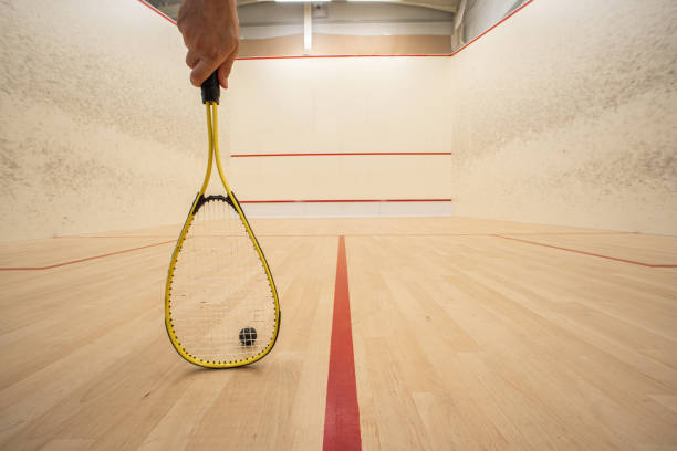 mano masculina sosteniendo una raqueta dentro de una cancha de squash. ángulo bajo, persona irreconocible, gran profundidad de campo - tennis indoors court ball fotografías e imágenes de stock