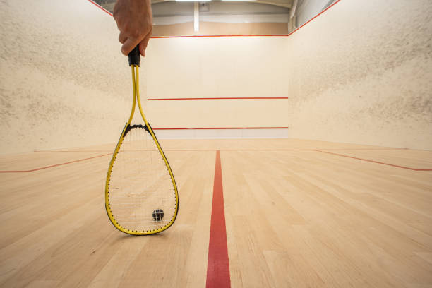 Male hand holding a racket inside a squash court. Low angle, unrecognizable person, large depth of field stock photo