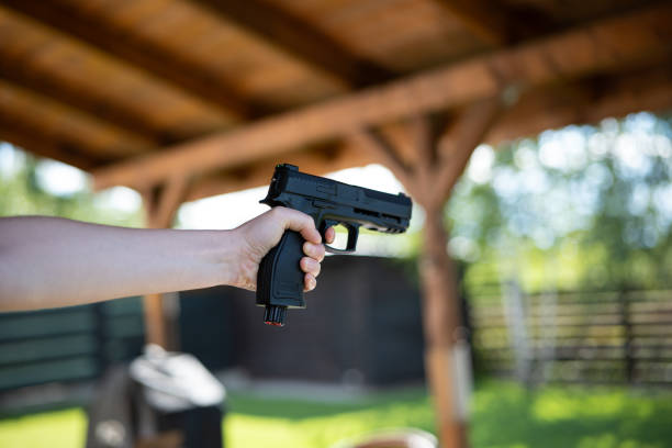 Unrecognizable woman holding and aiming a black air bb gun stock photo