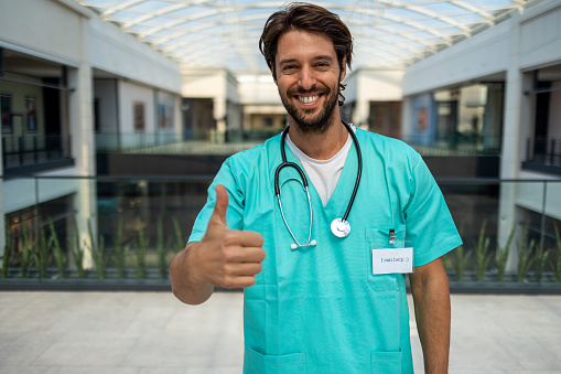 Smiling male nurse with thumb up at the hospital