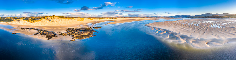 A drone aerial view of a small rocky beach on a sunny day