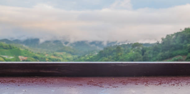 picture of a brown wooden table that is wet The background image is an unfocused mountain view. stock photo