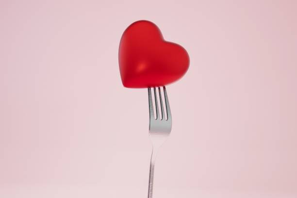 istock Valentine' day dinner. a red heart pricked on a fork on a pink background. 3D render 1429058140