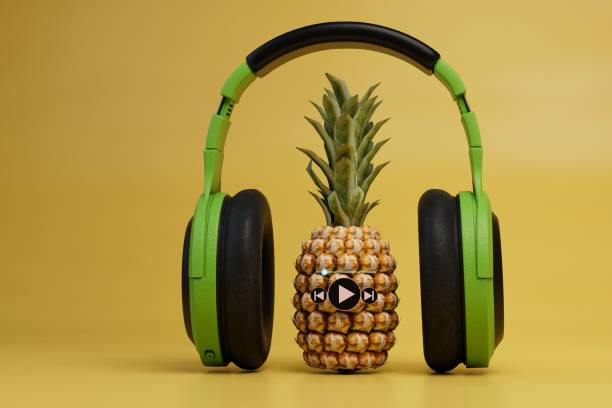 istock pineapple with a music track in headphones on a yellow background. 3D render 1429059577