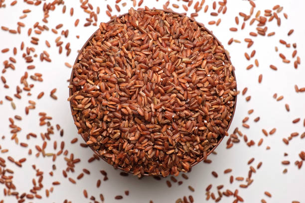 Dry Rice in wooden Bowl. Long Brown Rice Rotating. Close Up. Grains fall poured a stack. World crisis, export, import. Harvest problems, sanctions. Increase prices and shortages of food supplies