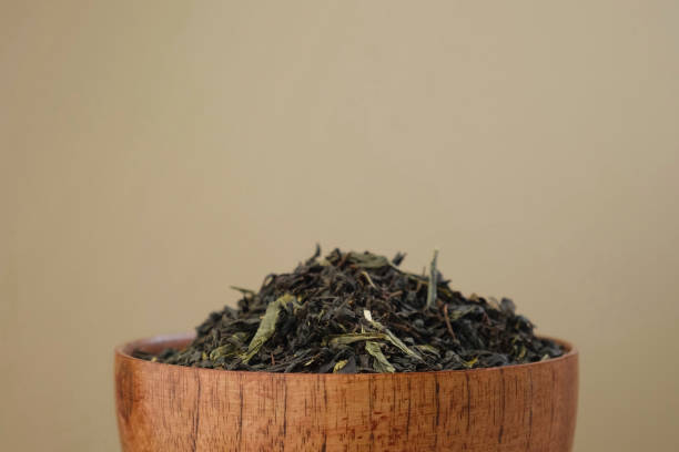 tè nero secco versato in una ciotola. mucchio di foglie di tè nero e verde mix. primo piano, macro. vista frontale. trama. spazio di copia. il tè essiccato sta girando, ruotando sul giradischi. sfondo di cibi e bevande - tea leaves chinese tea green tea tea foto e immagini stock