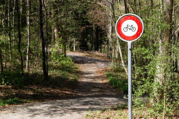 traffic sign bicycling on this forest path is prohibited, focus is on the red and white traffic sign, background is intentionally blurred, daytime sunshine