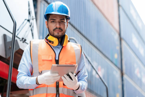 istock Dock manager man or engineer worker holding tablet and check stock in shipping container yard with smile. Import and export product. Manufacturing transportation and global business concept 1429066334