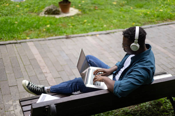 istock Man sitting on a park bench and using a laptop to study 1429072210