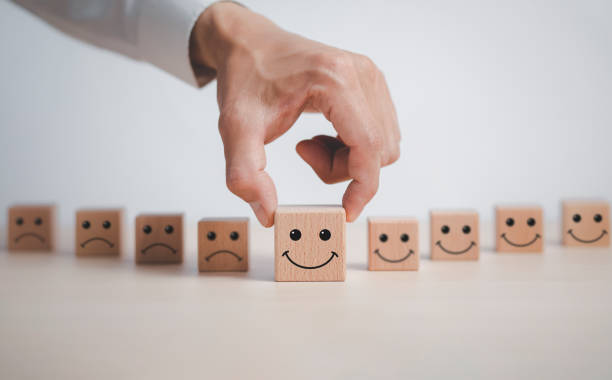 istock Customer service evaluation and satisfaction survey service rating concepts.Hand choose wooden cube block with icon face smile, Close up customer hand choose the happy face smile face icon on wooden. 1429073727