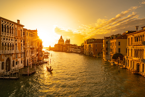 Sunrise over the canale grande (grand canal) in venice with one single gondolieri in his traditional gondola