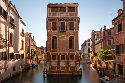 Old house in Venice between two tiny waterways and other traditional buildings on sunny day, long exposure