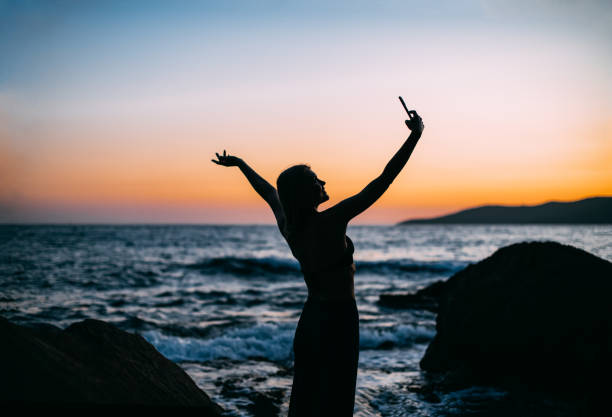 istock Young Woman Taking Selfie on the Beach at Sunset 1429076170