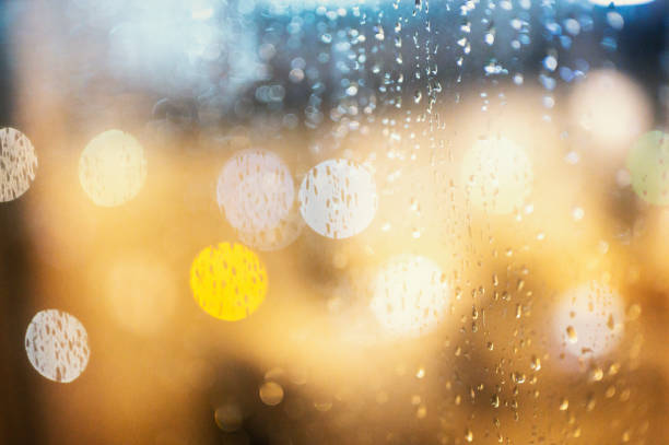 Close up Rain falling on window with traffic night light BG bokeh night